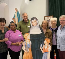 SSND Associates gather together for a photo with a life-size cutout image of Blessed Theresa