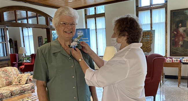 Sister Sue Von Bank, 60-year Jubilarian, and Sister Mary Ann Kuhn, Community Leader pinning flowers for an in-house Jubilee Celebration at OLGC. 