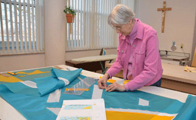 Sister Josephine Niemann works on a piece in Liturgical Fabric Arts.