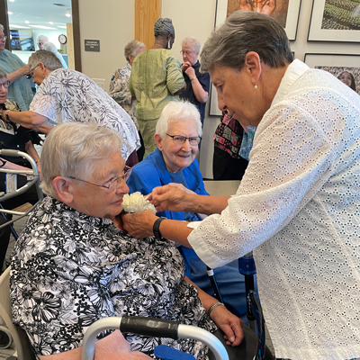 A fellow sister pins a white flower corsage to the shirt of one of the members of the class of 2024 Jubilarians ahead of the celebratory Mass at Prior Lake, Minnesota