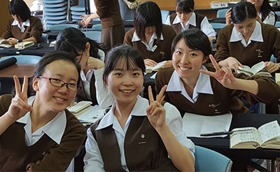 Three students pose for a picture in their classroom at Notre Dame Jogakuin Jr. and Sr. High School in Kyoto, Japan.