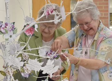 Sisteres Ancilla Roussel and Lorraine Landry place a memory flower on a tree in dedication and celebration of 145 years at St. Mary of the Pines in Chatawa, Mississippi.